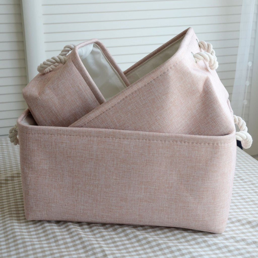 Paniers de rangement en tissu empilables rose posés sur un tapis de trois taille différentes S/M/L 